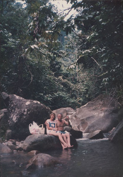 Two people sitting on rocks in a stream, enjoying each other's company.